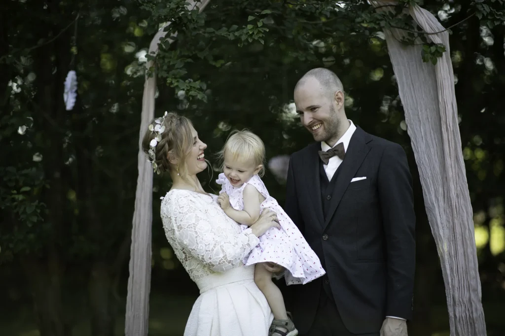 Brud med lille datter på armen ved siden af brudgommen