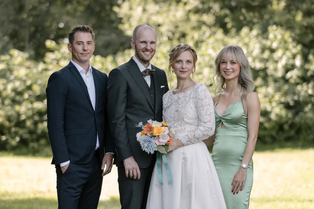 Brudepar med to bryllupsgæster i haven