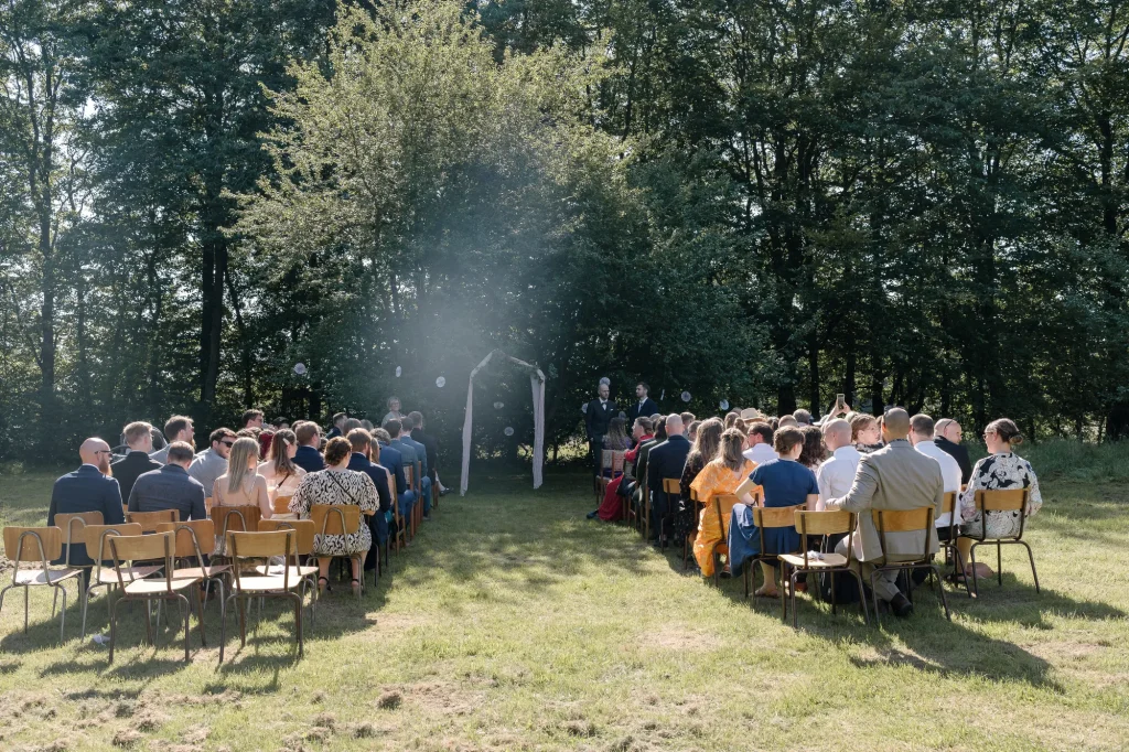 Udendørs vielse med gæster på stole i skoven