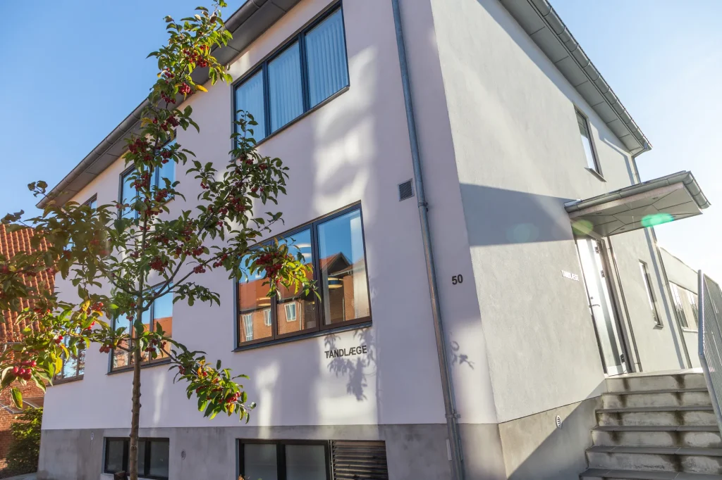 Tandklinikkens hvide facade med træ foran indgangen