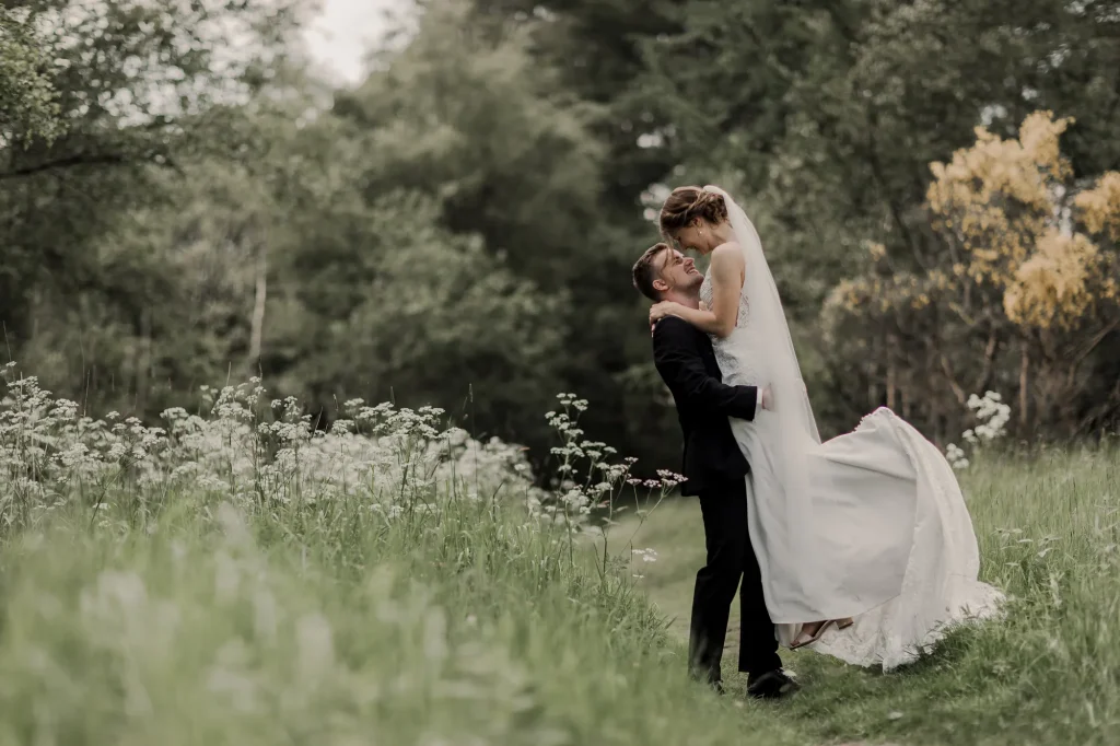 Brudgom løfter bruden i en blomstrende eng – bryllupsbillede fra Tine & Jesper