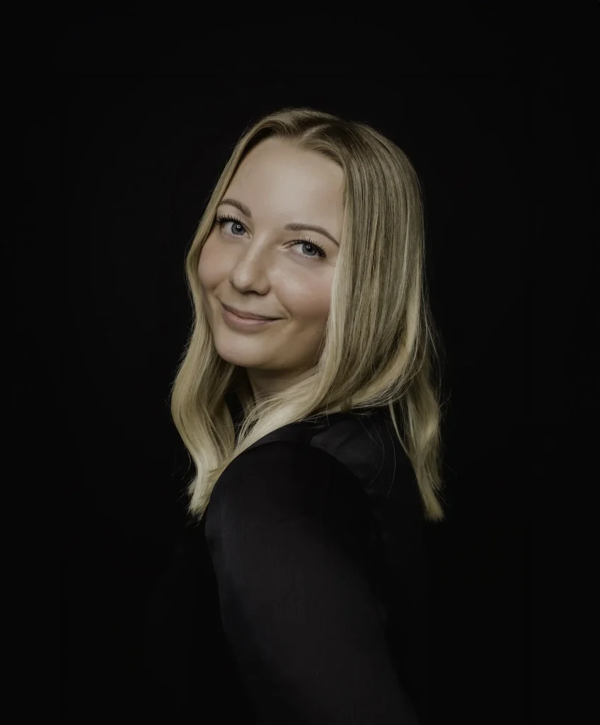 Portræt af smilende kvinde med lyst hår foran sort baggrund